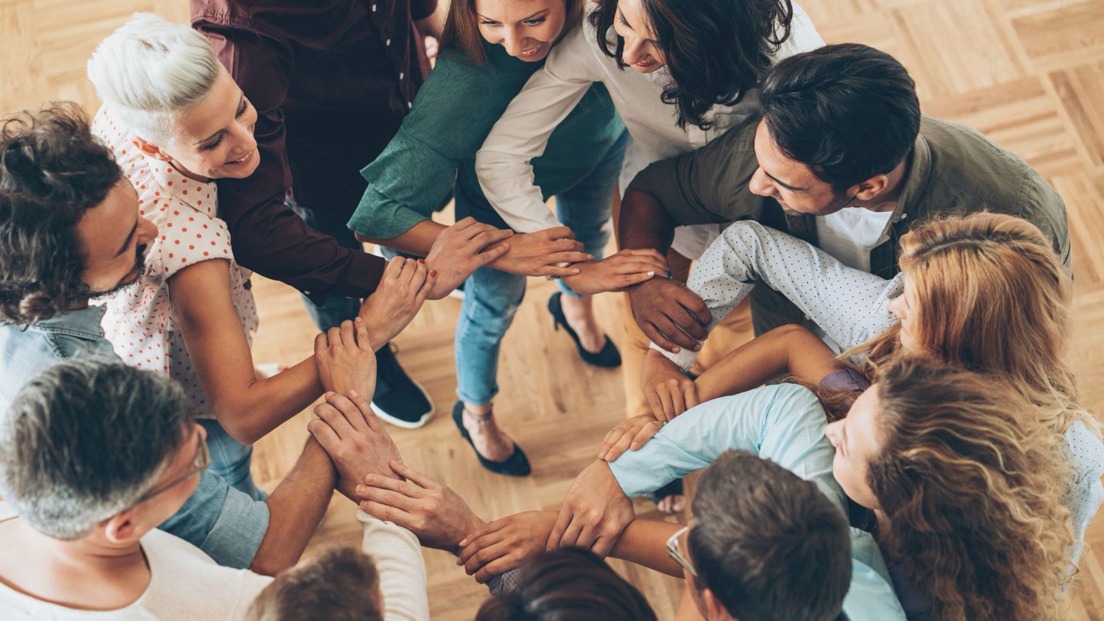 A group of people are standing in the circle and holding hands